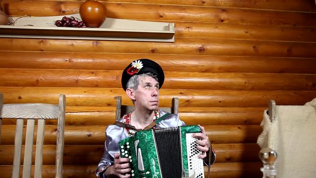 Russian man in russian national  is playing accordion. clothes 