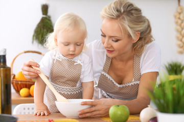 Obraz na płótnie Canvas Happy family in the kitchen. Mother and child daughter cooking tasty breakfest