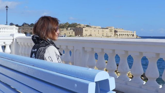 lonely widow sitting on the bench looking the sea