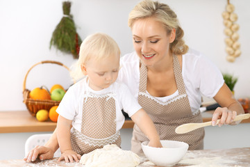 Happy family in the kitchen. Mother and child daughter cooking holiday pie or cookies for Mothers day, casual lifestyle photo series in real life interior