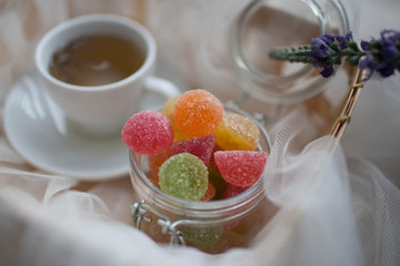 Cup of tea and marmalade in a jar lay in the cart covered with a white silk cloth