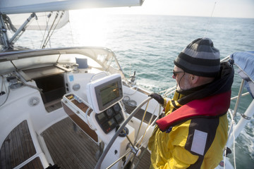 Mature Man Steering Wheel Of Yacht In Sea