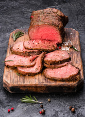 Roast beef on cutting board with salt and pepper.