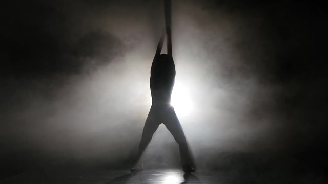Silhouette leggy girl dancing in a smoky studio rhythmic dance