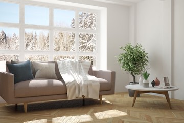 White room with sofa and winter landscape in window. Scandinavian interior design