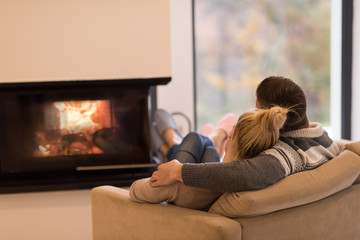 Young couple  in front of fireplace - obrazy, fototapety, plakaty