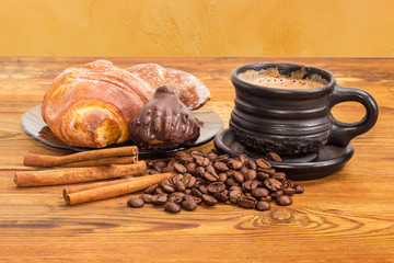 Brewed coffee, coffee beans, cinnamon sticks, chocolate truffle and croissant
