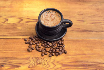 Coffee in black cup and coffee beans on wooden surface