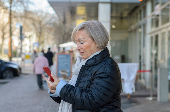 Senior woman using mobile in city street