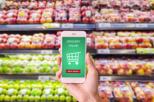 Woman Hand Holding Mobile With Grocery Online On Screen With Blur Supermarket Background