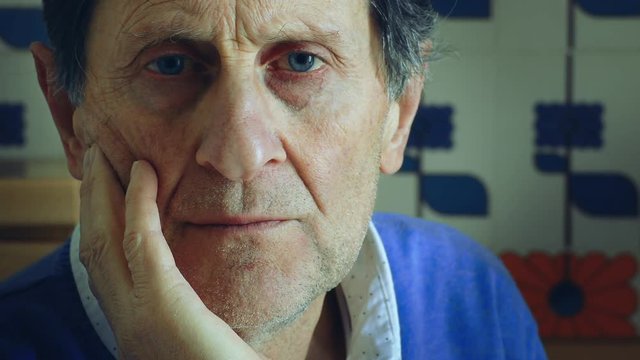 sad and depressed old man meditates looking at the camera,closing eyes