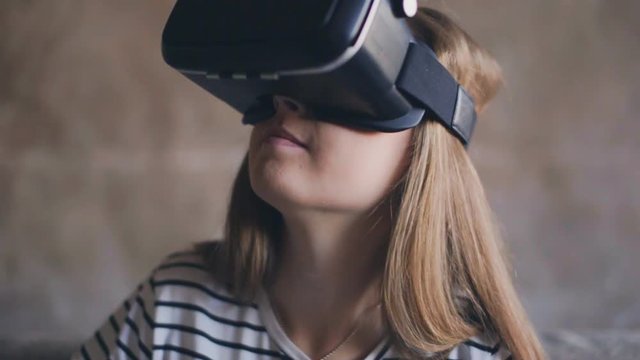 Young woman enjoying high technology of virtual reality glasses at home.