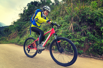 Fototapeta na wymiar young woman riding mountain bike on forest trail