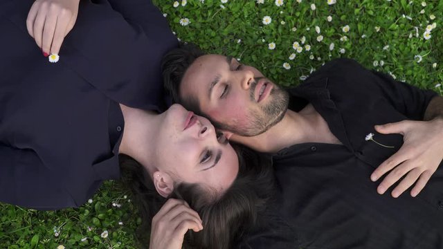 young lovers lying on the grass talking amiably