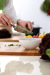 Closeup of human hands cooking vegetables salad in kitchen on the glass table with reflection. Healthy meal and vegetarian concept
