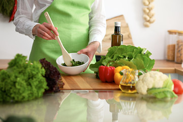 Closeup of human hands cooking vegetables salad in kitchen on the glass table with reflection. Healthy meal and vegetarian concept