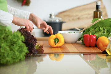 Closeup of human hands cooking vegetables salad in kitchen on the glass table with reflection. Healthy meal and vegetarian concept