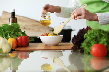 Closeup of human hands cooking vegetables salad in kitchen on the glass table with reflection. Healthy meal and vegetarian concept