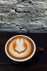 Coffee cup with latte art on the wood table