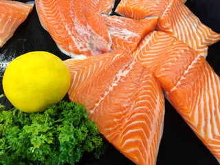 Fresh salmon and lemon on black background.