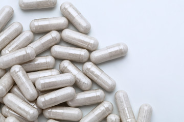 Pile of capsules with probiotic powder inside on white background. Top view, high resolution...