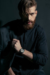 Fototapeta na wymiar Stylish handsome bearded man hipster with jacket on shoulder looking at camera