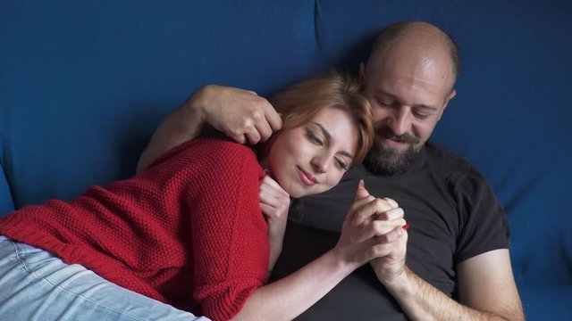 tender couple on blue sofa is cuddling gently