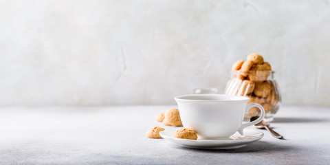 White cup of coffee with amaretti cookies on light gray background with copy space.