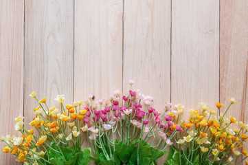 Artificial flowers on wooden plank with copy space.