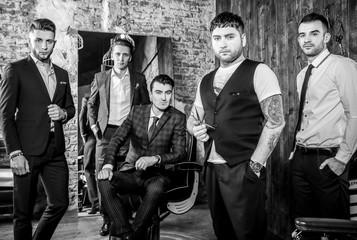 Group of young elegant positive mens pose in interior of barbershop. Black-white photo.