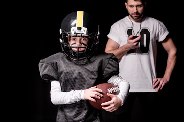 Trainer with sport timer looking at boy american football player