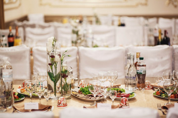 flowers in transparent vases with water and appetizer standing on table