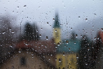 Rain drops on window with house and church in background