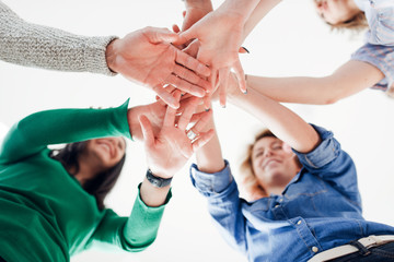 Group of positive-looking young  colleagues in a hands in huddle