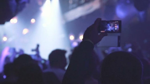 People taking photos or recording video with their smart phones at music concert. Night party, night rave.