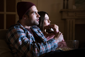 side view of concentrated couple watching movie at home