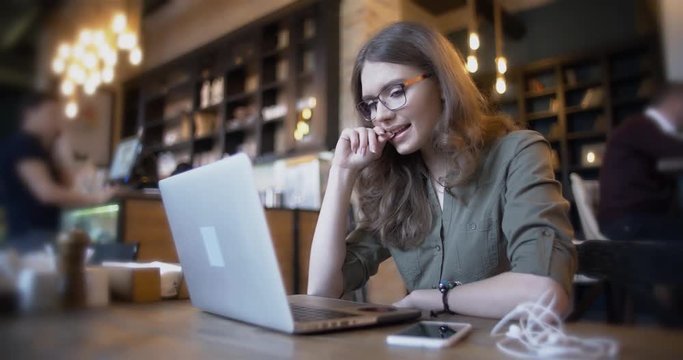 Young woman working on modern laptop in cafe 4k