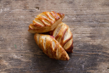 Three fresh croissants on old wooden table