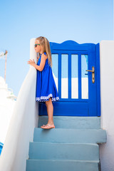 Little girl at street of typical greek village with white walls and steps in Greece