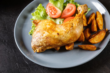 Roasted chicken legs with potato wedges and tomatoes