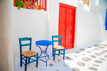 Blue chairs and table on street of typical greek traditional village with white houses on Mykonos...