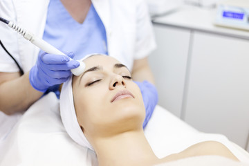 Skin care. Young woman receiving facial beauty treatment. Facial therapy. Anti-aging procedures.