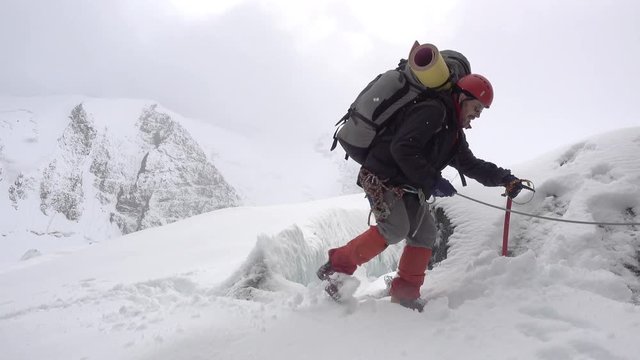 Mountain climber stepping over crevasse on mountain