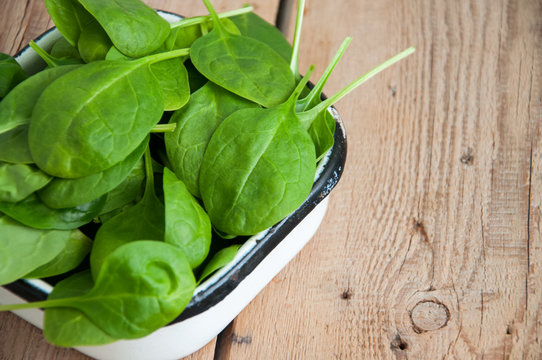 Fresh baby spinach leaves on a wooden background