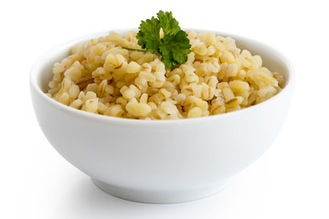 Cooked bulgur wheat with green parsley in white ceramic bowl isolated on white.