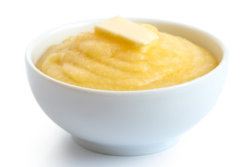 Cooked cornmeal polenta with butter in white ceramic bowl isolated on white.