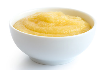 Cooked cornmeal polenta in white ceramic bowl isolated on white.