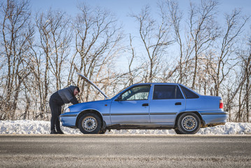 man repairing a car standing at the hood