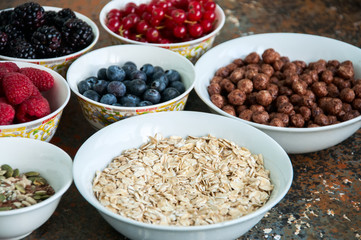 Oat, berries, superfood seeds in bowls on a rusty background
