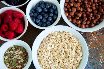 Oat, berries, superfood seeds in bowls on a rusty background
